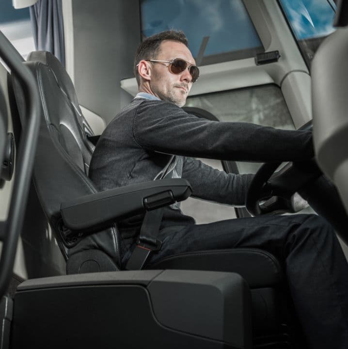 A professional bus driver sits at the wheel of a bus